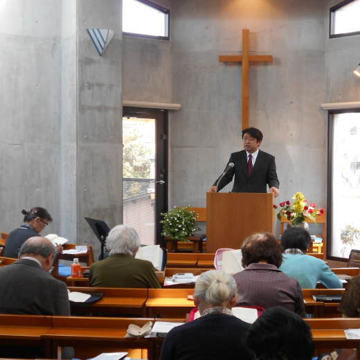 礼拝に集う人々と聖書からメッセージを伝える牧師